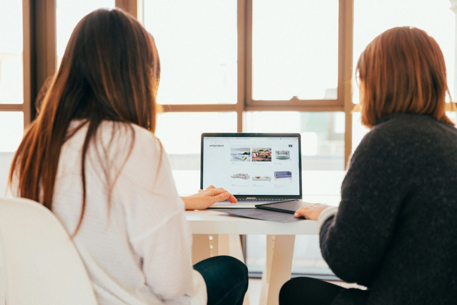 Twee collega's overleggen achter een laptop